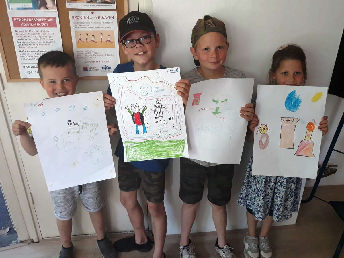 Kinderen laten hun tekeningen zien die zij maakten voor de prullenbakkenkunst in Hofwijk